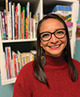 Author photo of Patty Cisneros Prevo wearing a red turtleneck and glasses in front of a bookshelf