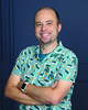 Steve Asbell author photo showing him wearing a blue patterned shirt and crossing his arms in front of a deep blue background.