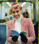 A. M. Dassu author photo showing her in a red jacket, white shirt, and red and white hijab standing on a bus holding a book.